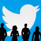 Black silhouettes of people are shown in front of Twitter's white bird logo against a blue background.